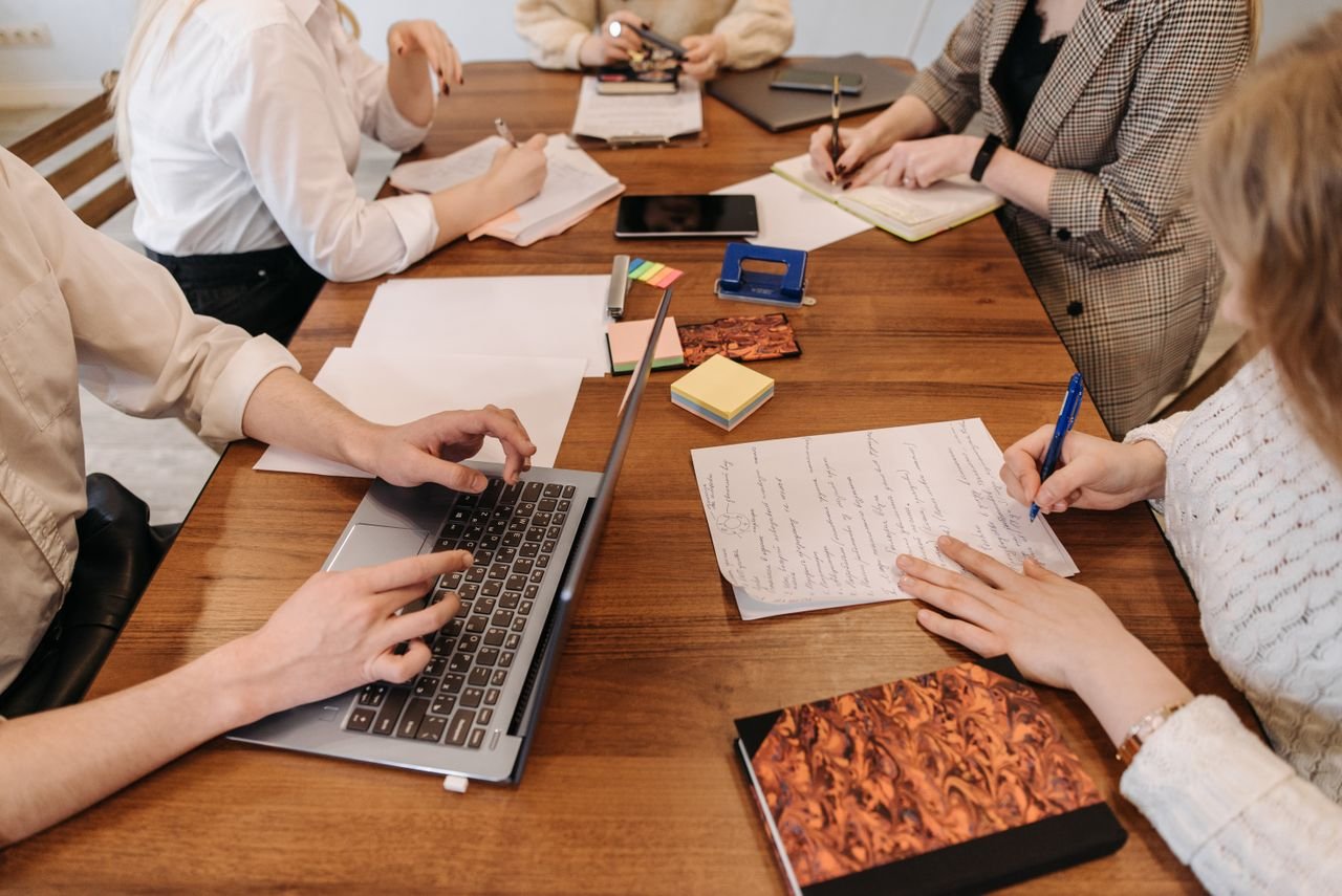 A group of professionals collaborating during a meeting with laptops and notepads.